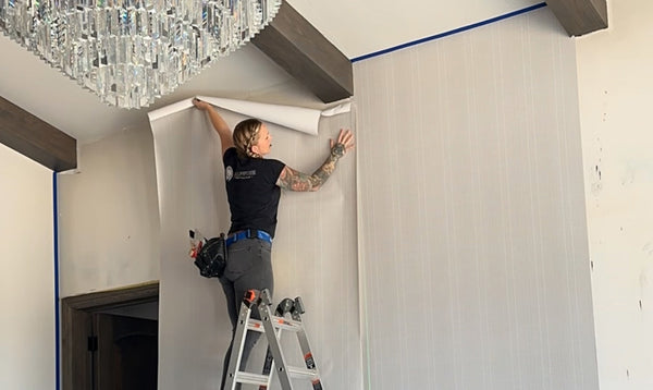 Professional wallpaper installer on a ladder